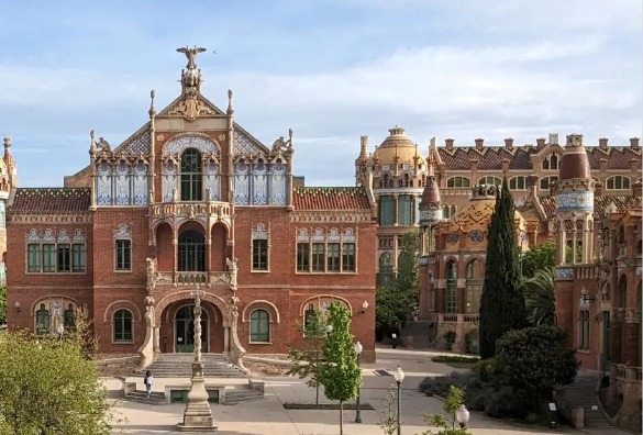 Exterior view of the main entrance facade of the Hospital de Sant Pau, showcasing the stunning modernist architecture of Lluís Domènech i Montaner.